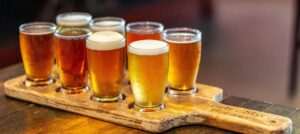 wooden paddle holding a flight of small beer glasses in different shades