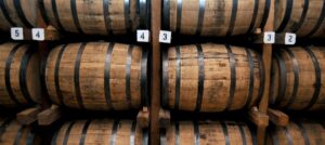 rows of wooden barrels stacked on racks in a cellar