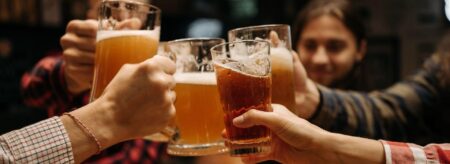 group of friends clinking beer glasses together in a bar