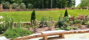 Stone bench overlooking blooming flower beds and green lawn at Sarah P. Duke Gardens in Durham.