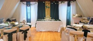 Wedding reception setup inside the Carriage House featuring elegantly decorated tables, a sweetheart table with floral accents, and green, gold, and white wedding decor.