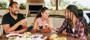 Three friends are eating and toasting while smiling at each other